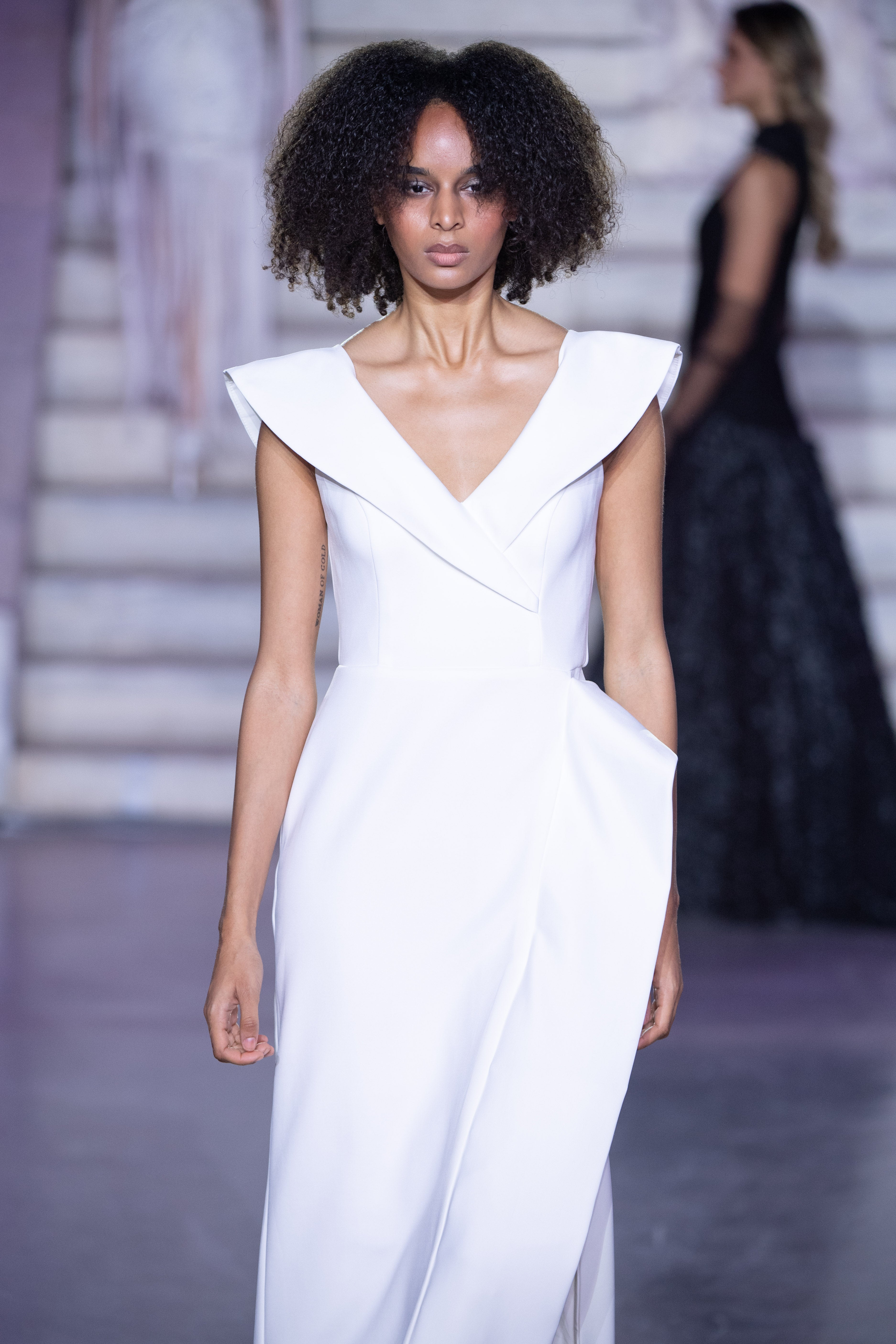 Petra Kara Aegean Architectural Dress displayed on a hanger with intricate blue and white patterns and flowing fabric.