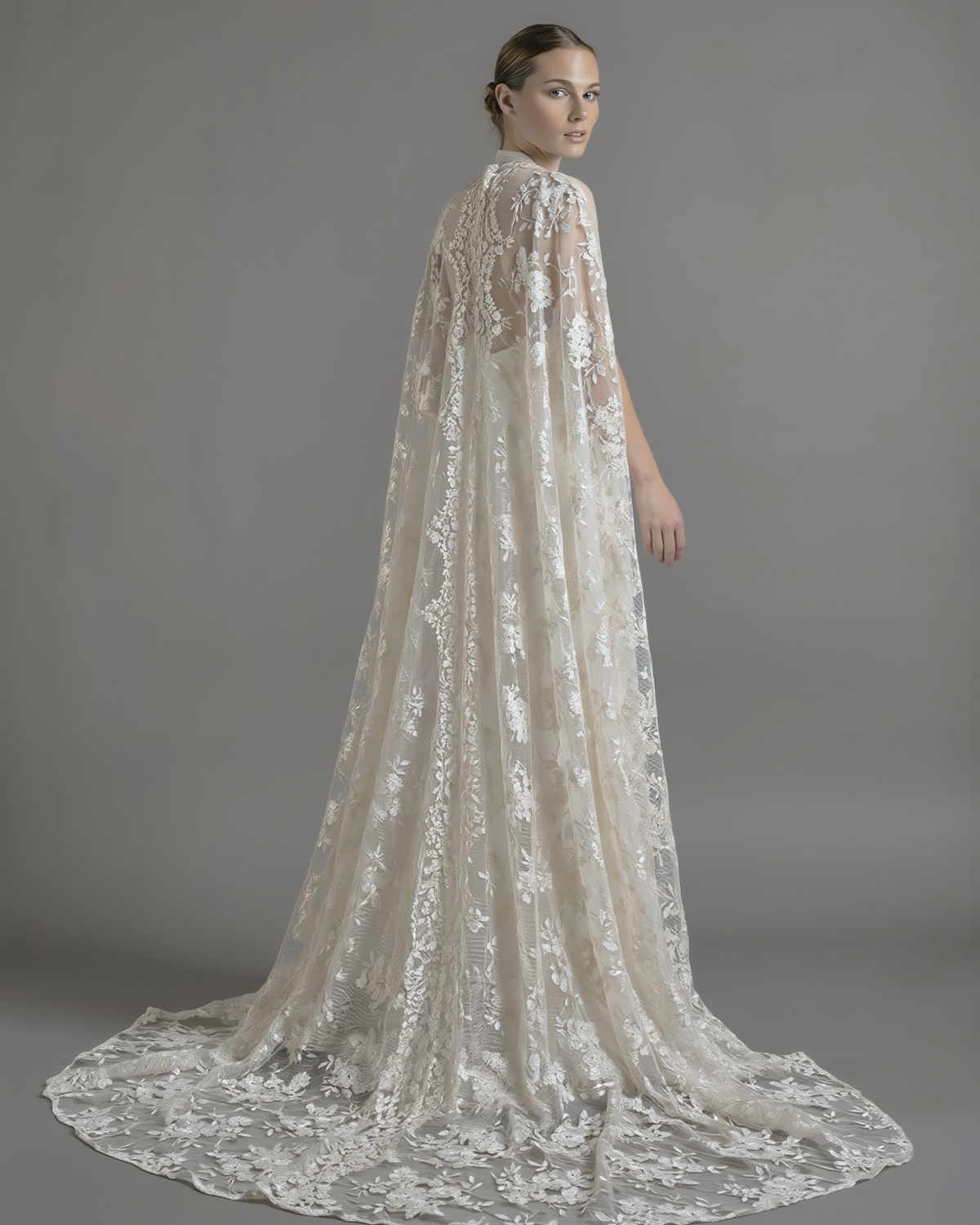 Elegant dramatic lace cape from Petra Kara Bridal, shown in size S-XXXL, featuring intricate lace detailing and flowing fabric.