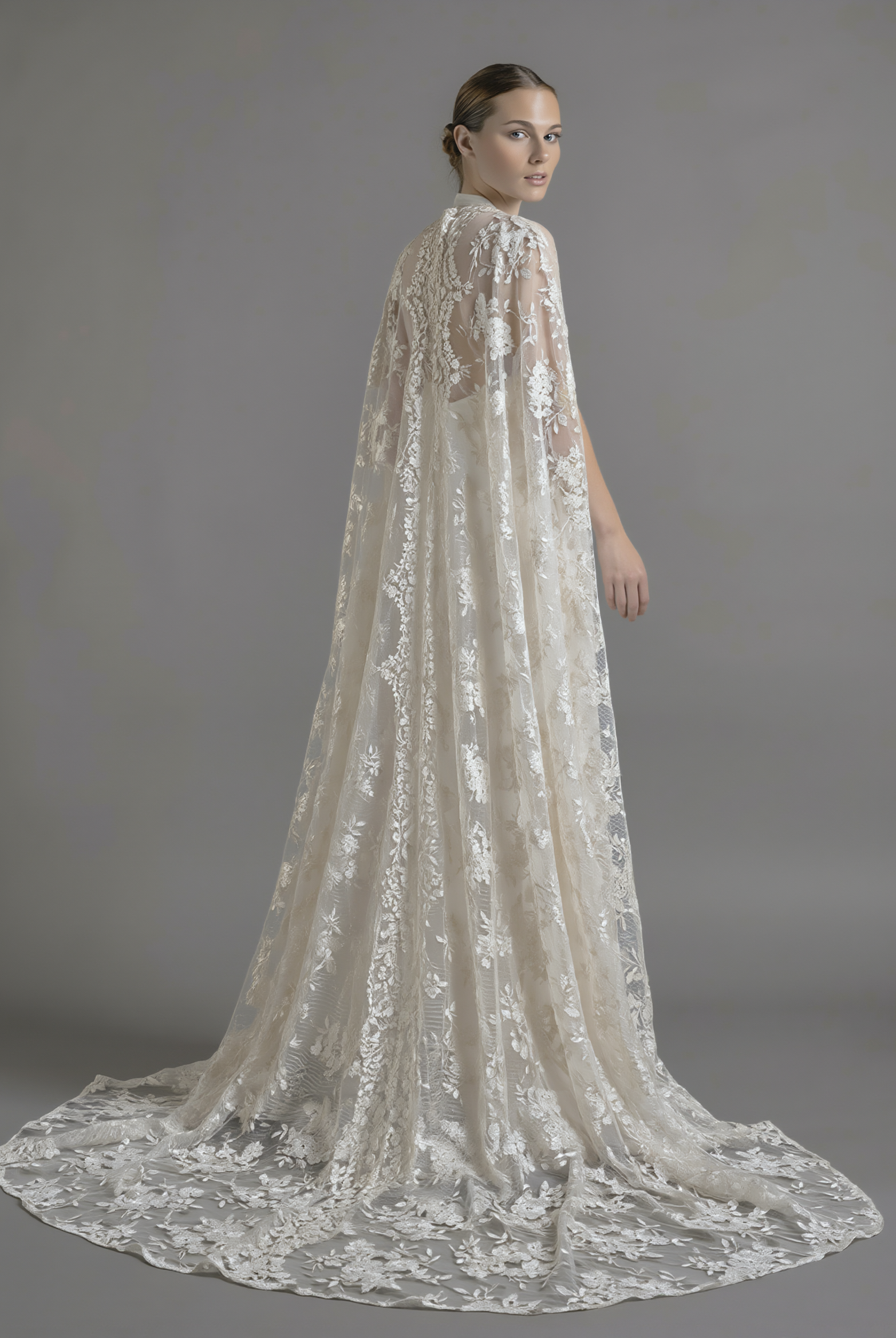 Elegant dramatic lace cape from Petra Kara Bridal, shown in size S-XXXL, featuring intricate lace detailing and flowing fabric.
