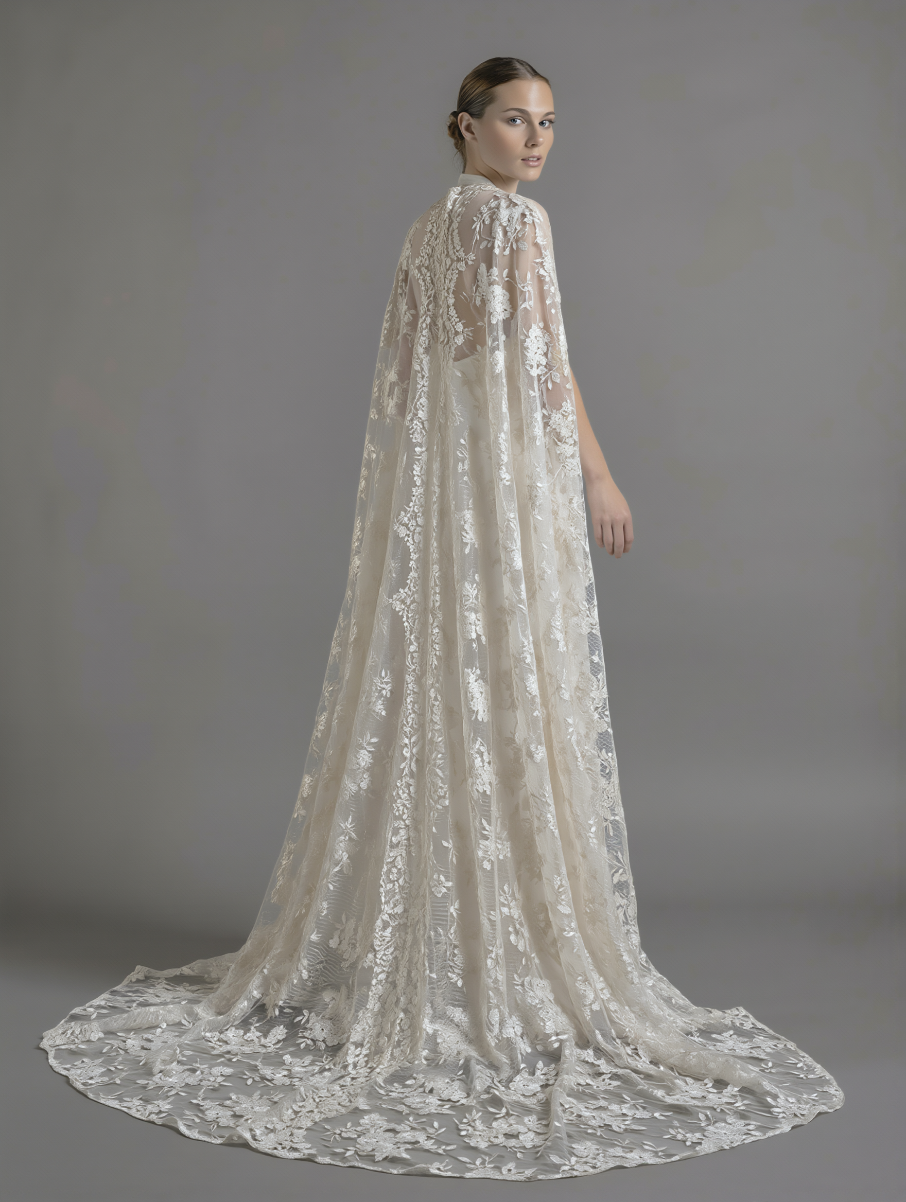 Elegant dramatic lace cape from Petra Kara Bridal, shown in size S-XXXL, featuring intricate lace detailing and flowing fabric.